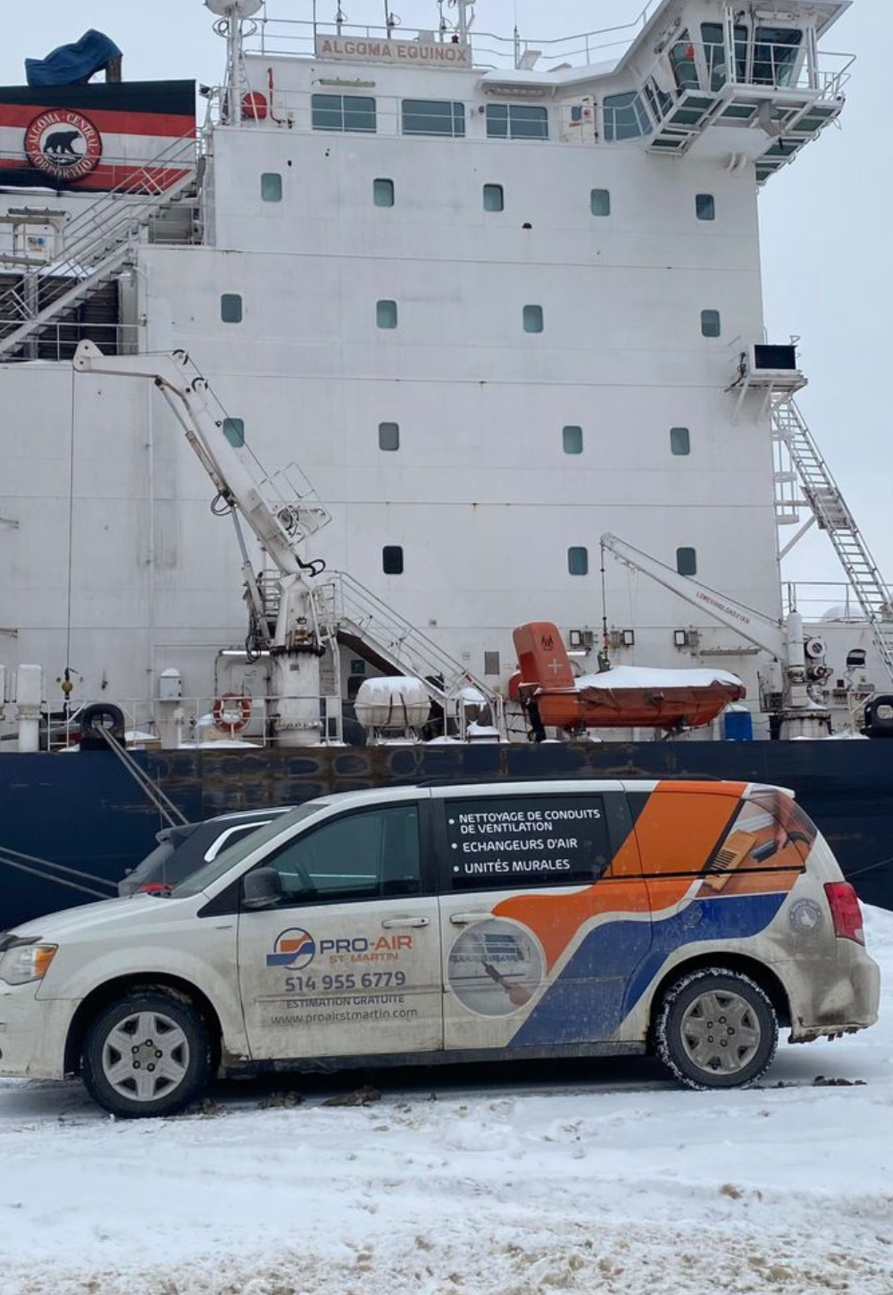 Véhicule de service Pro-Air stationné près d'un grand navire de transport, avec des équipements visibles sur le navire.